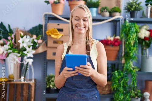 Young blonde woman florist smiling confident using touchpad at florist store