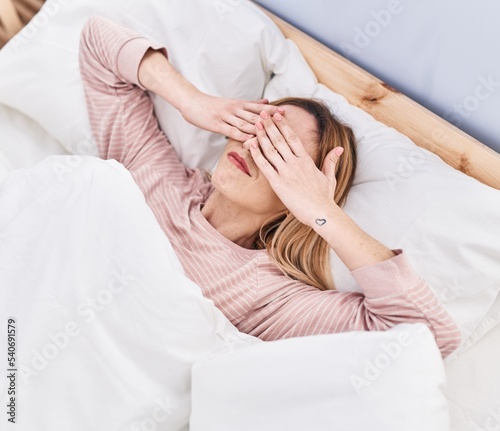 Young blonde woman stressed lying on bed at street