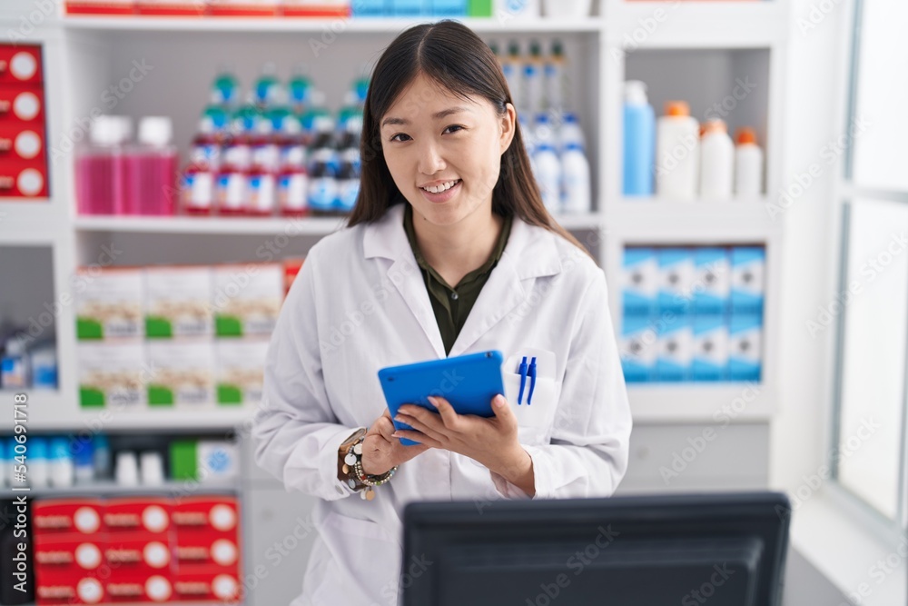 Chinese woman pharmacist using touchpad working at pharmacy Chinese woman pharmacist using touchpad working at pharmacy