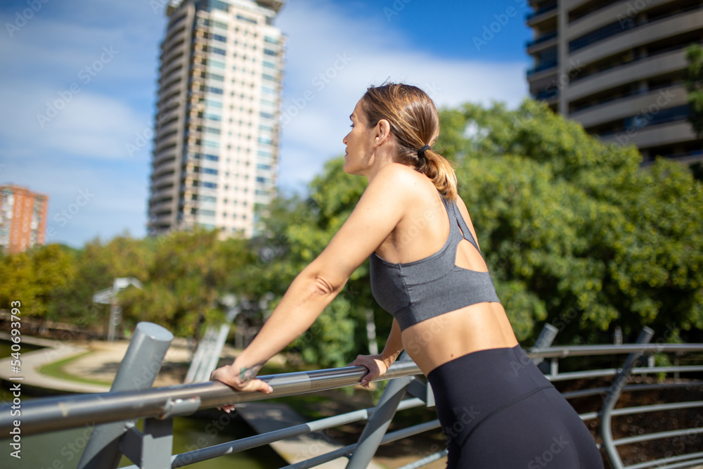 side of sport female leaning against by railing