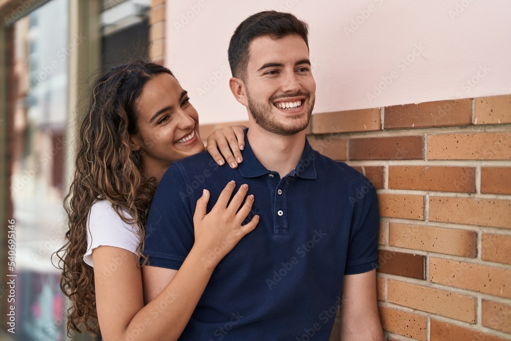 Fototapeta premium Young hispanic couple smiling confident hugging each other at street