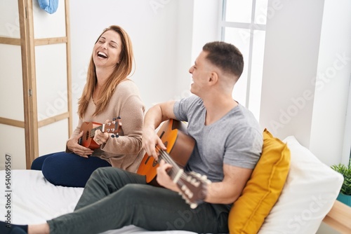 Man and woman mother and son playing classical guitar and ukulele at bedroom