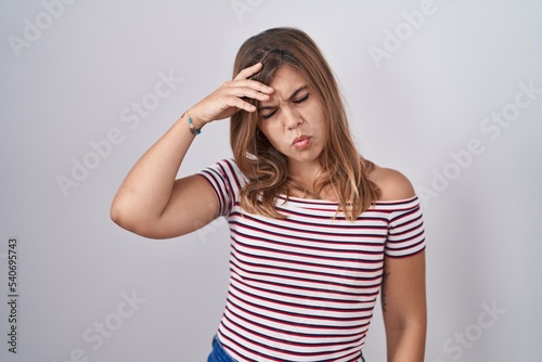 Young hispanic woman standing over isolated background worried and stressed about a problem with hand on forehead, nervous and anxious for crisis