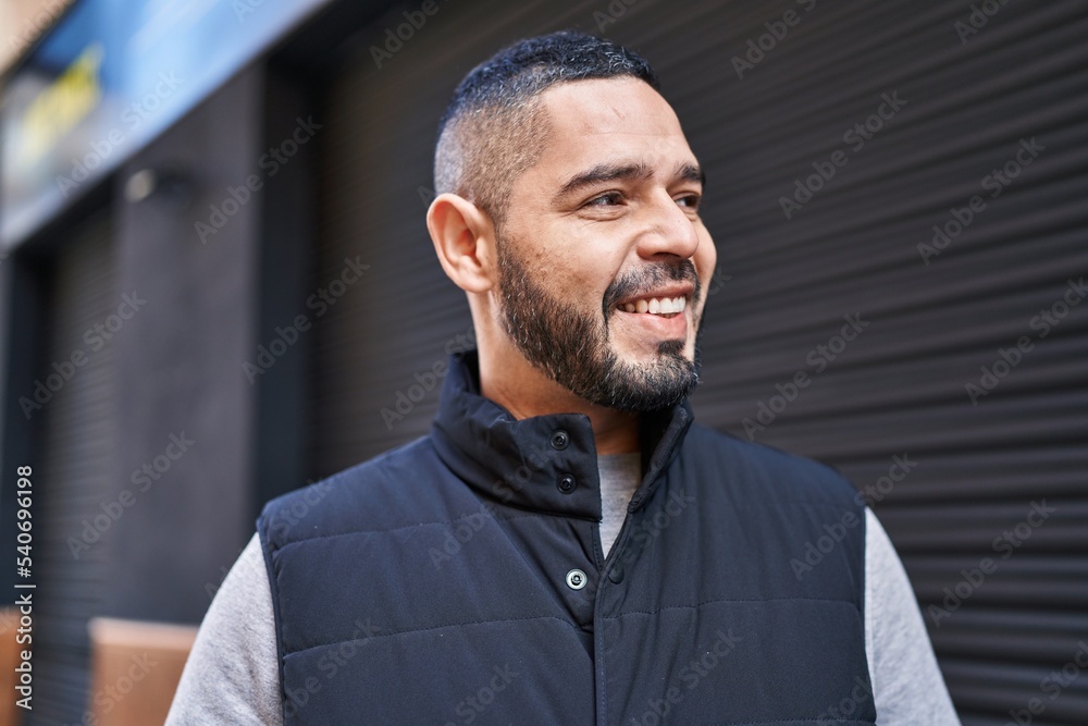 Obraz premium Young latin man smiling confident looking to the side at street