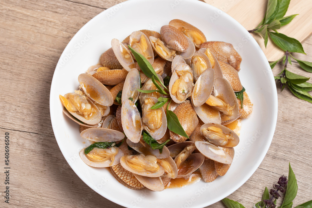 Stir fried clams with basil leaves in a white bowl Stir fried clams with basil leaves in a white bowl