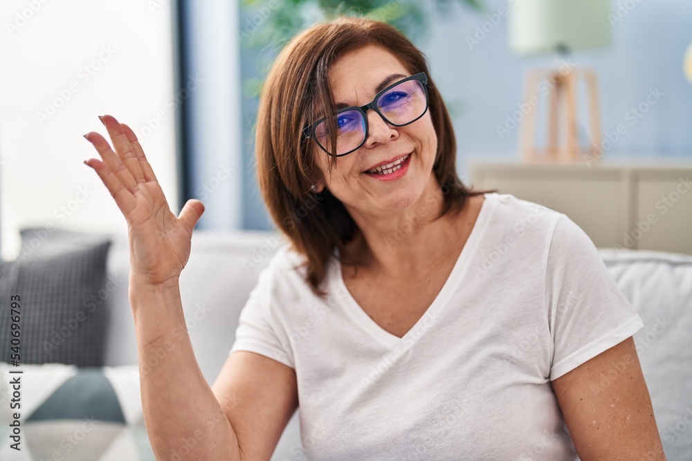 Middle age woman sitting on sofa speaking at home Middle age woman sitting on sofa speaking at home