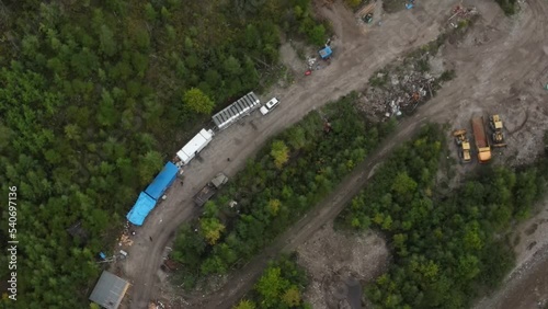 View from above. Industrial mining of alluvial gold in the protected river. Camp prospectors in the protected forest. Trailers with workers by the river.
