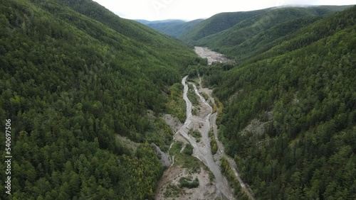 View from above. Industrial mining of alluvial gold in the protected river. The industrial road passes by a stream developed by miners in a green valley.