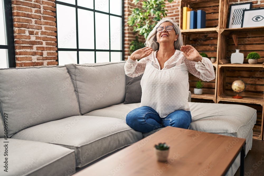 Fototapeta premium Middle age woman sitting on sofa suffering for back pain at home