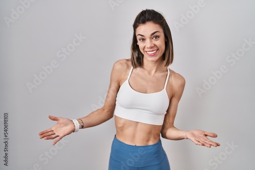 Hispanic woman wearing sportswear over isolated background smiling cheerful with open arms as friendly welcome, positive and confident greetings