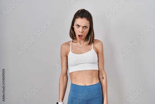 Hispanic woman wearing sportswear over isolated background in shock face, looking skeptical and sarcastic, surprised with open mouth © Krakenimages.com