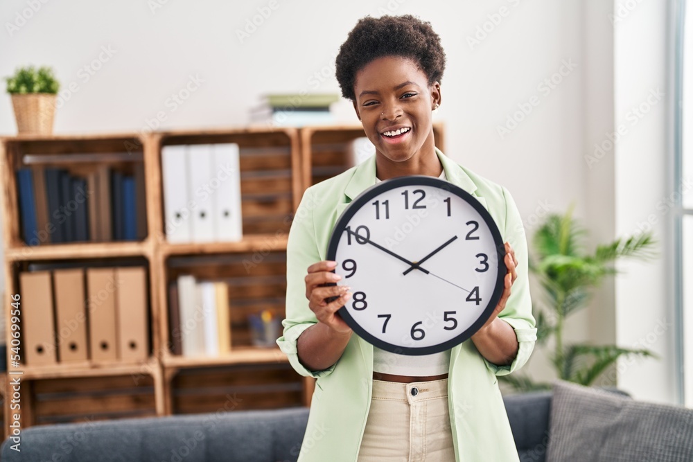 African american woman holding big clock smiling and laughing hard out loud because funny crazy joke. African american woman holding big clock smiling and laughing hard out loud because funny crazy joke.