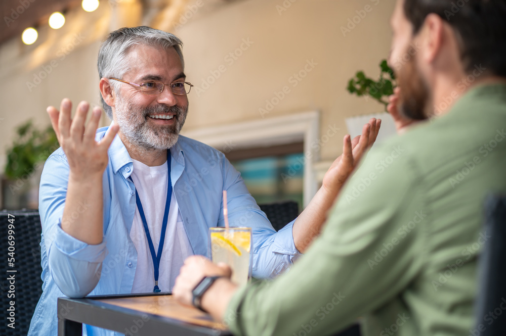 Two men sitting in the cafe and having an interesting conversation Two men sitting in the cafe and having an interesting conversation