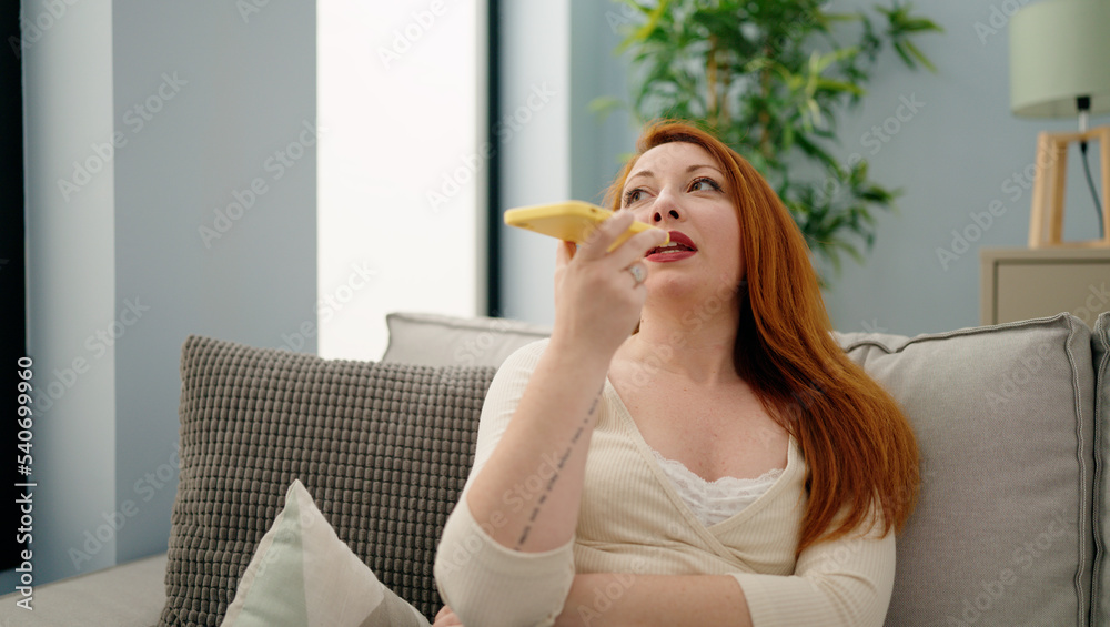 Young redhead woman talking on the smartphone sitting on sofa at home Young redhead woman talking on the smartphone sitting on sofa at home
