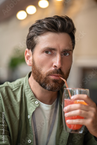 Young bearded man sitting in the cafe and having a break in work