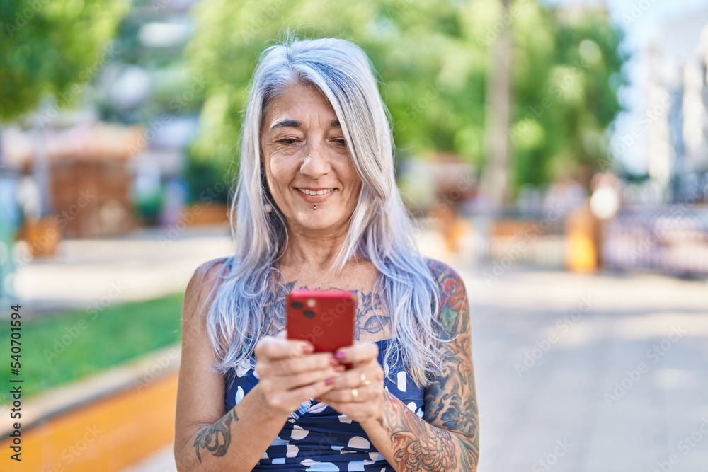 Middle age grey-haired woman smiling confident using smartphone at park Middle age grey-haired woman smiling confident using smartphone at park
