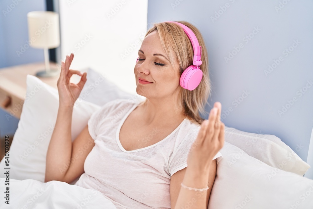 Young blonde woman doing yoga exercise sitting on bed at bedroom Young blonde woman doing yoga exercise sitting on bed at bedroom