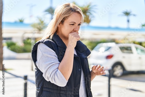 Young blonde woman coughing at park