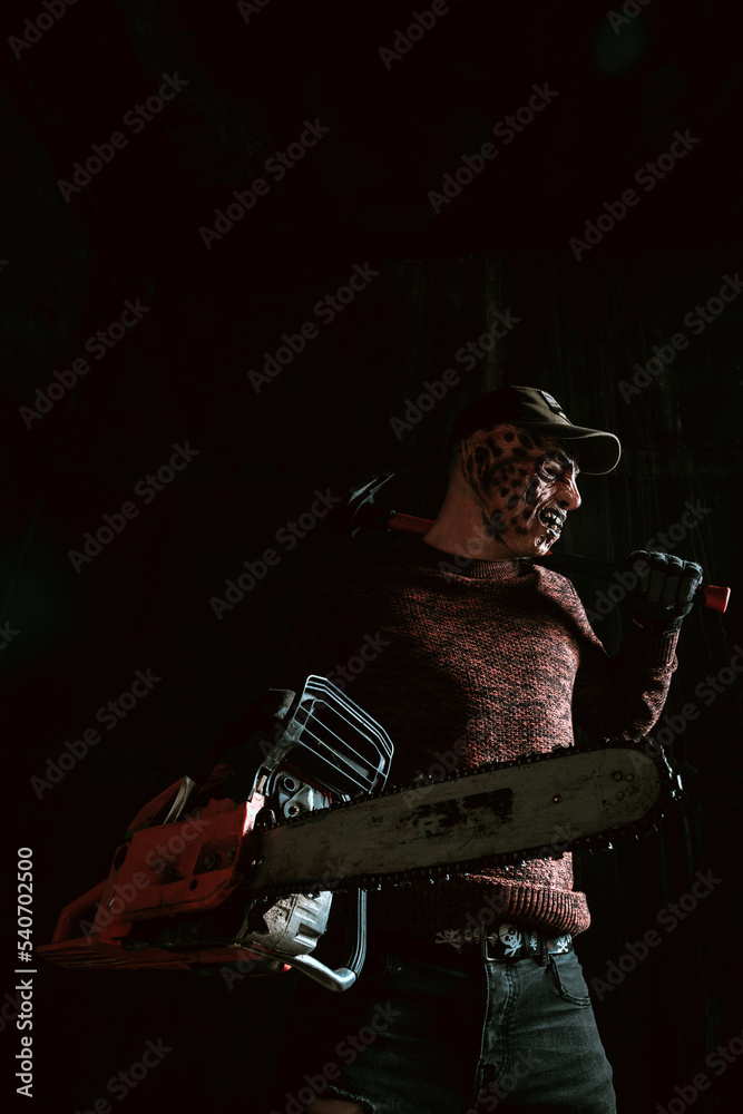 Evil in mask with chainsaw, horror Halloween scene in dark room