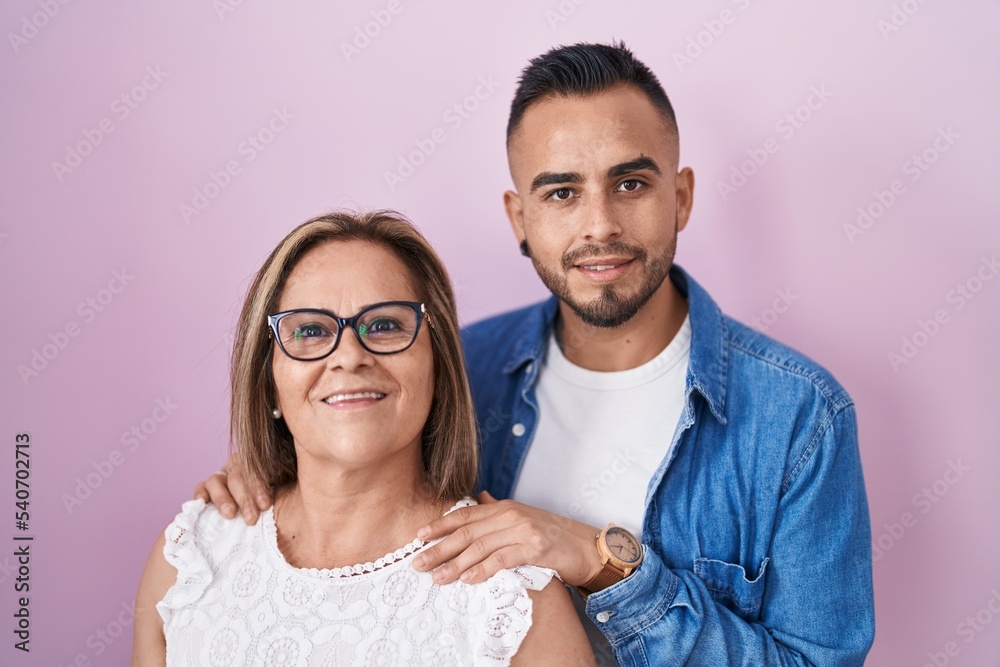 Hispanic mother and son standing together smiling with a happy and cool smile on face. showing teeth. Hispanic mother and son standing together smiling with a happy and cool smile on face. showing teeth.