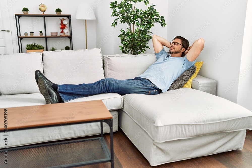 Obraz premium Middle age caucasian man relaxed with hands on head lying on sofa at home