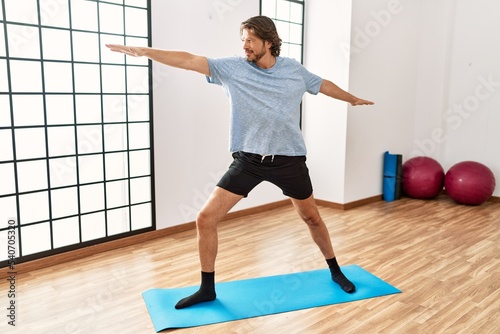 Middle age caucasian man smiling confident training yoga at sport center