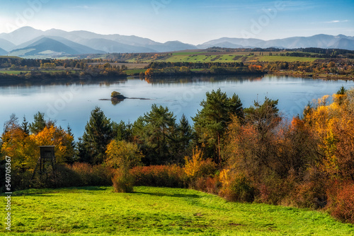 Colorful autumn landscape with lake, yellow trees and mountains at background