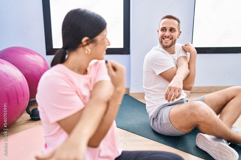 Man and woman couple smiling confident stretching at sport center