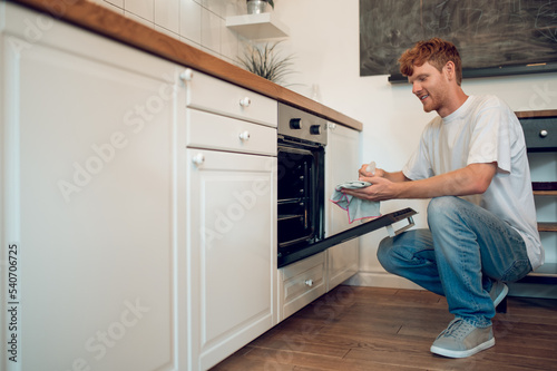 Ginger man in casual clothes near the oven in the kitchen