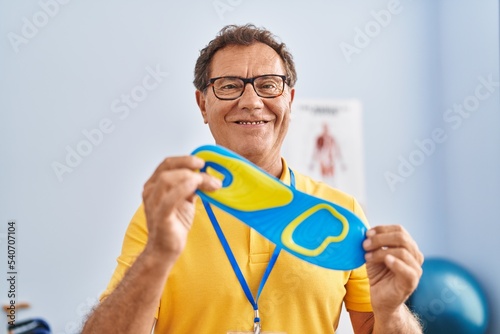 Middle age man podiatrist holding insole at physiotherpy clinic