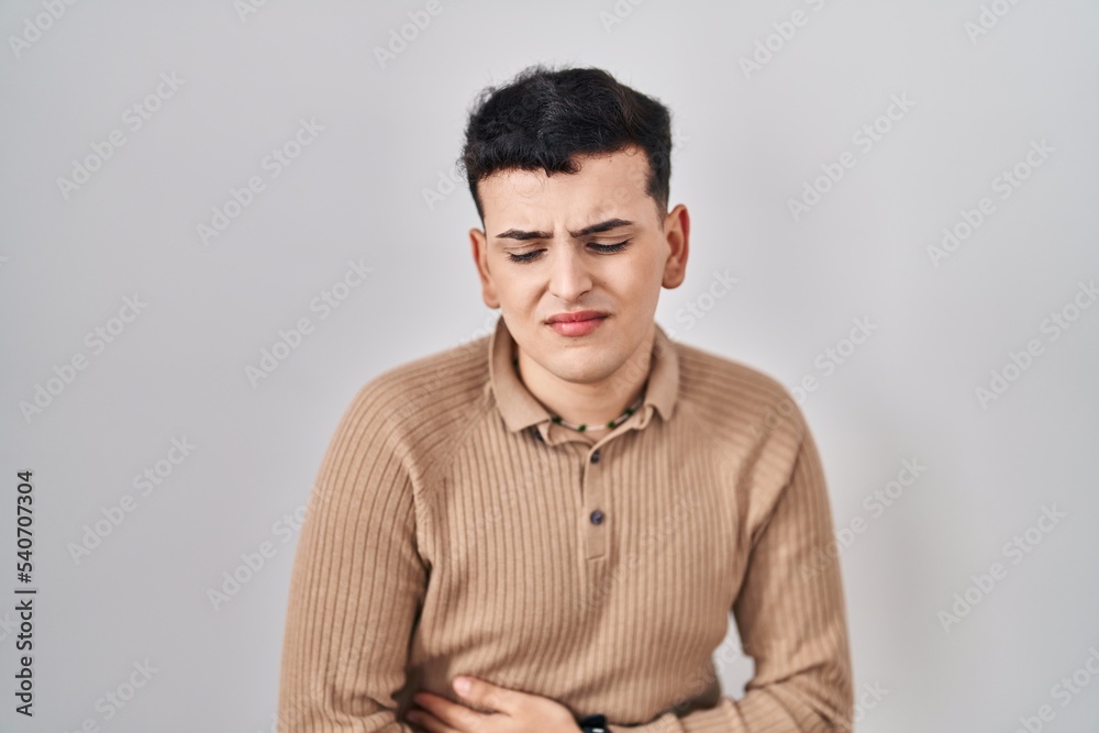 Non binary person standing over isolated background with hand on stomach because indigestion, painful illness feeling unwell. ache concept. Non binary person standing over isolated background with hand on stomach because indigestion, painful illness feeling unwell. ache concept.