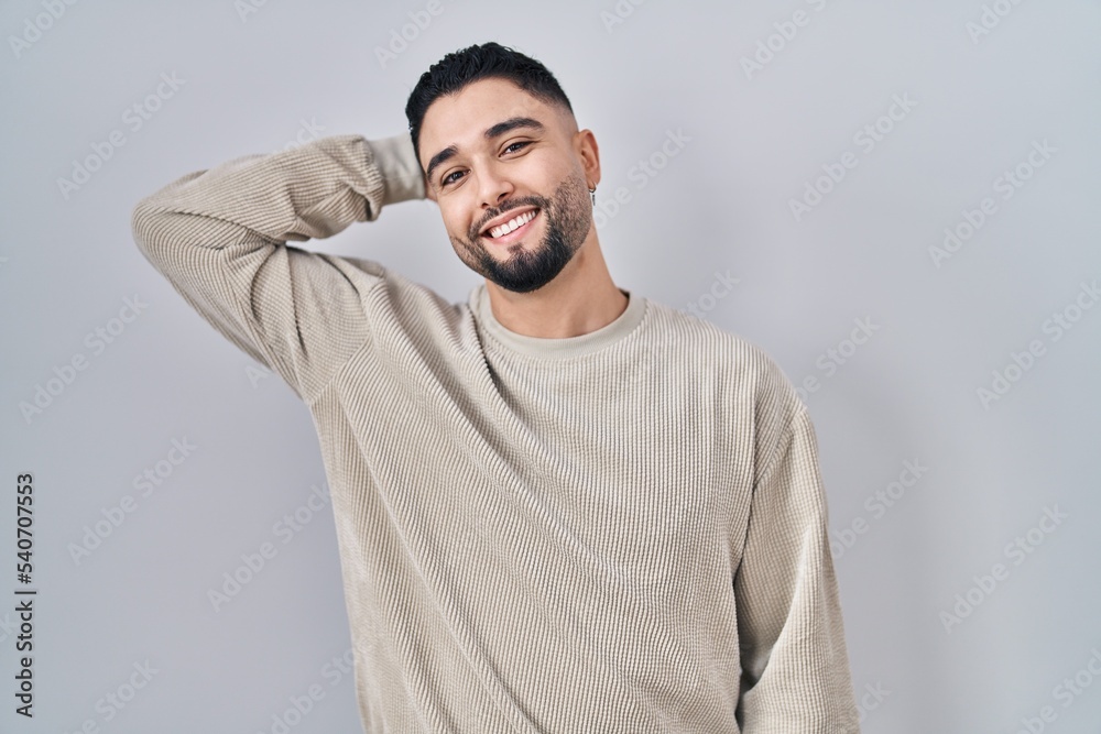 Young handsome man standing over isolated background smiling confident touching hair with hand up gesture, posing attractive and fashionable Young handsome man standing over isolated background smiling confident touching hair with hand up gesture, posing attractive and fashionable