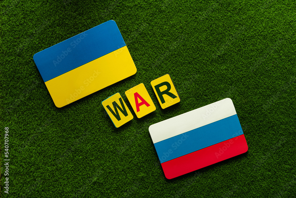 Fototapeta premium Ukraine Vs Russia. Symbol flags on a green lawn background.