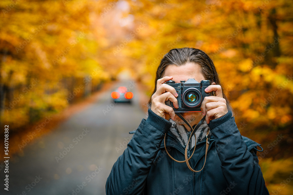 Man taking photo in autumn forest