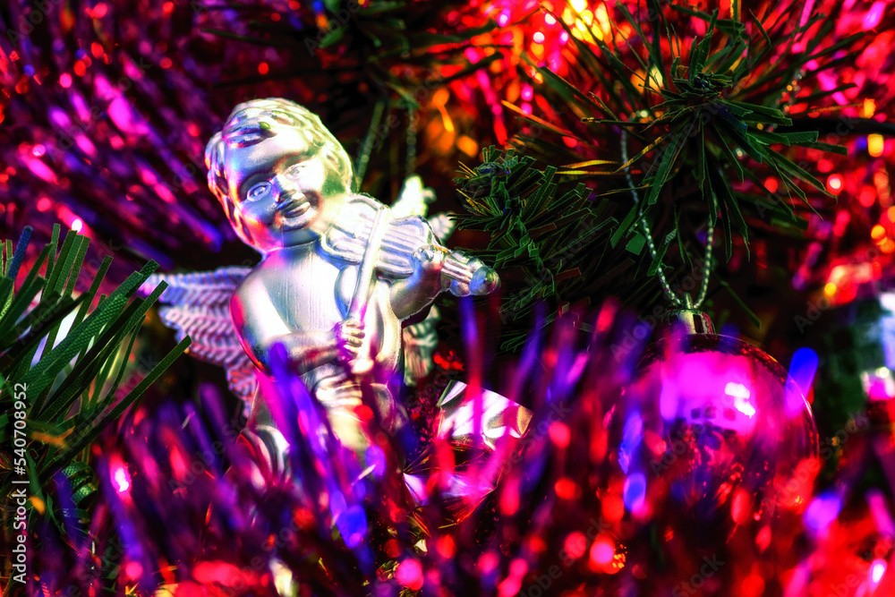Ball and cute toy angel with violin hanging on decorating a Christmas tree