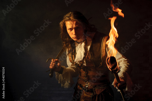 Εκτύπωση καμβά Young pirate filibuster with burning torch on dark brick background