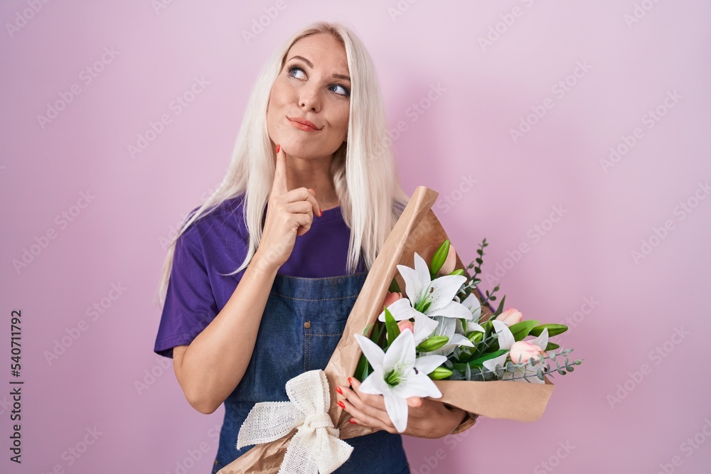 Caucasian woman holding bouquet of white flowers thinking concentrated about doubt with finger on chin and looking up wondering