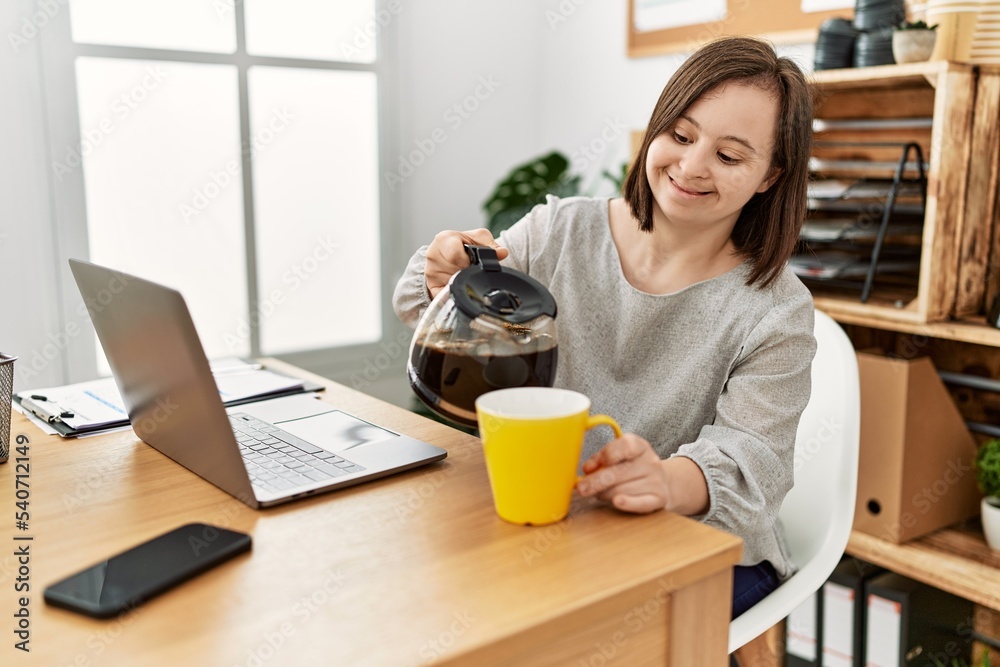 Brunette woman with down syndrome drinking a cup of coffee at business office