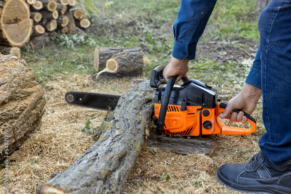 A chainsaw with an orange handle and sharp teeth in a rotating chain on a rail. Flying shavings from the saw. A chainsaw with an orange handle and sharp teeth in a rotating chain on a rail. Flying shavings from the saw.
