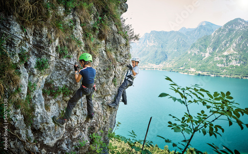 Girl with brother climbing mountain with Lake Idro in background photo