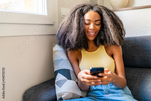 Woman with Afro hairstyle using mobile phone at home