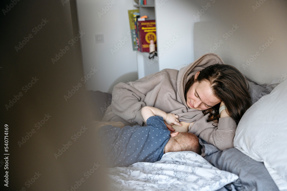 Mother breastfeeding boy on bed at home Mother breastfeeding boy on bed at home