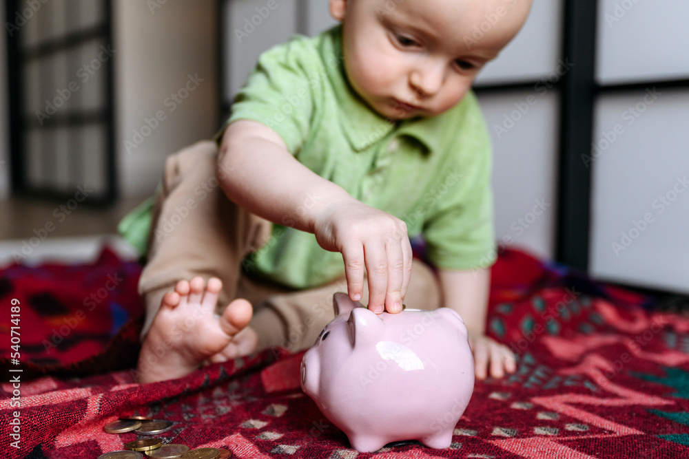 Baby boy putting coin in piggy bank Stock Photo | Adobe Stock