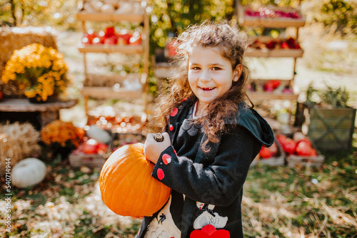 Smiling girl holding pumpkin at autumn fair on sunny day photo