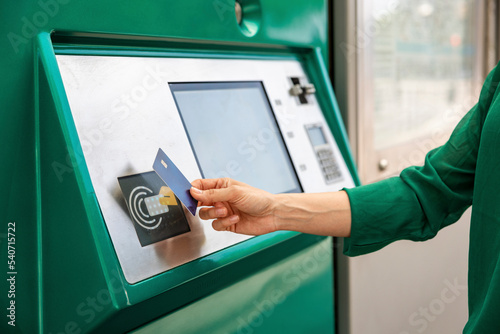Hand of woman tapping credit card on ticket machine at tram stop photo