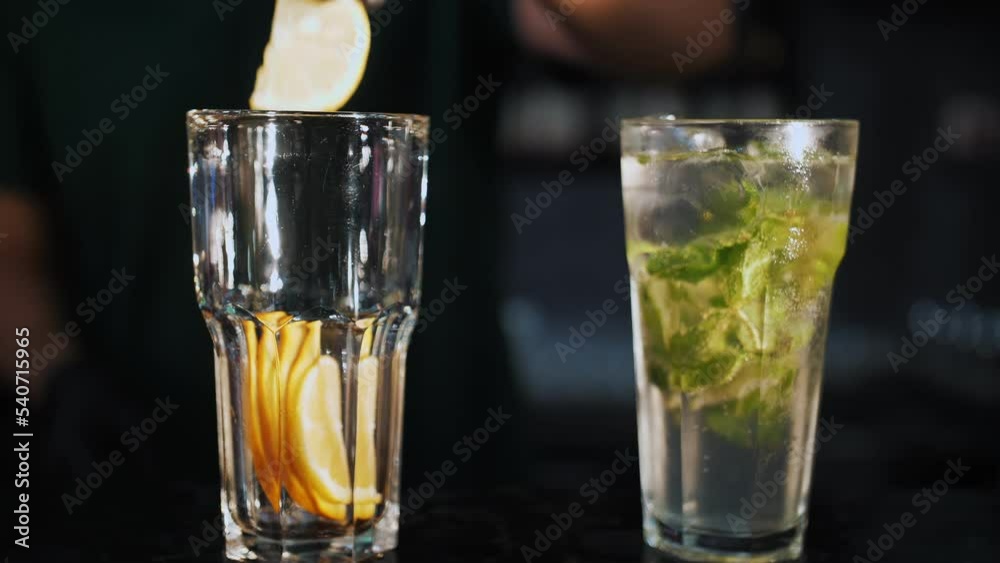 cocktail. Bartender makes cocktails. close-up. Bartender crushes mint leaves and slices of orange in a glass. Two cocktails on a black background