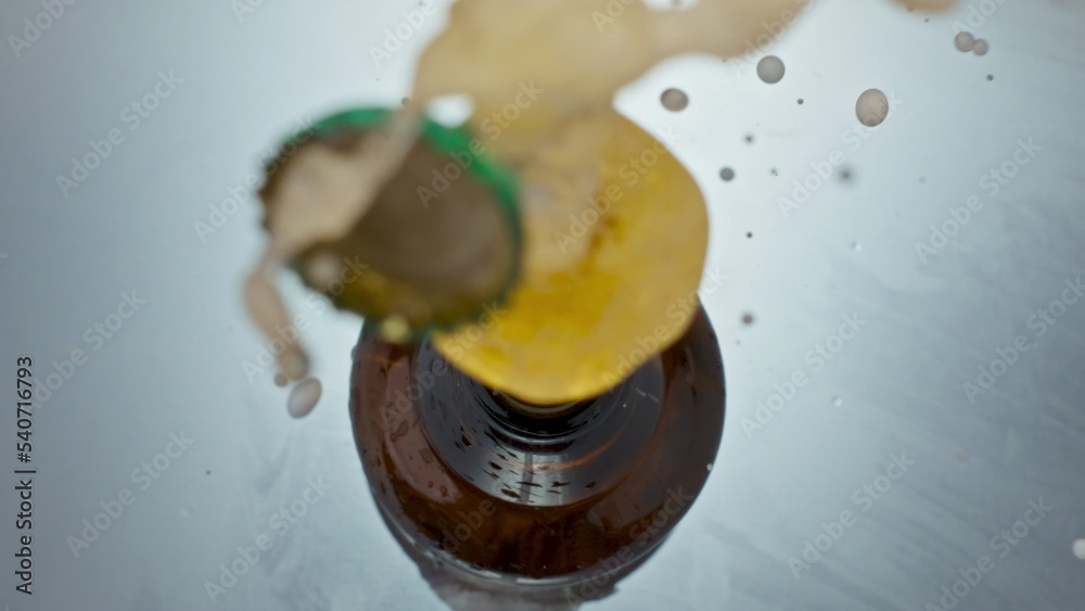 Fototapeta premium Uncorking bottled craft beer closeup. Unfiltered liquid splashing from flask