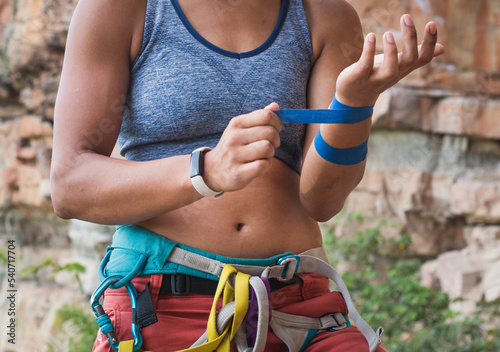 Strong female rock climber putting on tape