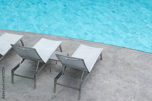 Gray pool lounge chairs by swimming pool.