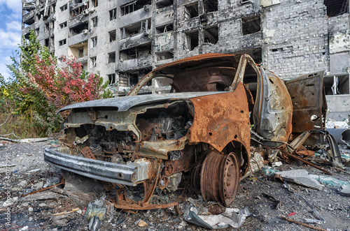 burnt blown up car against the background of a destroyed house in Ukraine